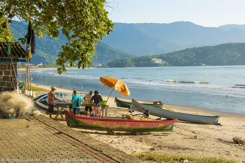 Imagem de pescadores limpando peixe na Praia do Itaguá.